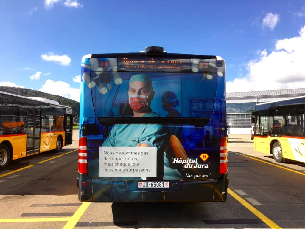 Bus avec un médecin avec un masque de spiderman ainsi que le slogan "Nous ne sommes pas des super héros, mais chaque jours nous nous surpassons".