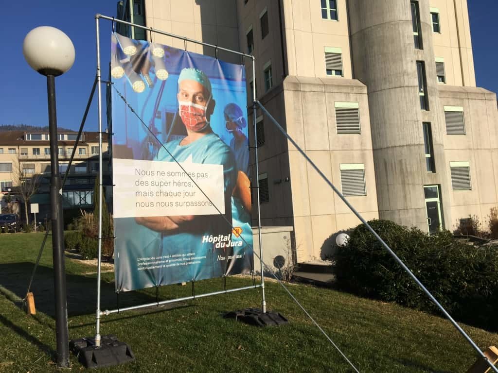 Affiche avec un médecin portant un masque spiderman ainsi que le slogan "Nous ne sommes pas des super héros, mais chaque jour nous nous surpassons".