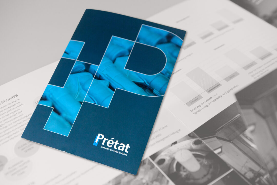 Brochure bleu avec écrit "Prétat", posé sur une brochure ouverte.