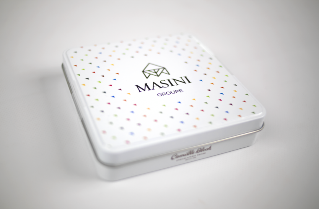 Photographie d'une boîte de chocolats dont le couvercle est recouvert d'un motif fait de triangles et au centre duquel figure le logo de Masini Groupe