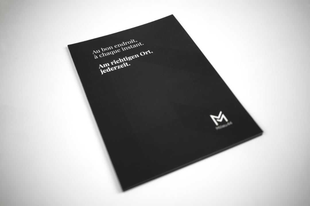 Couverture noire du porte-documents Milieu44 comportant le slogan au bon endroit à chaque instant en français et en allemand