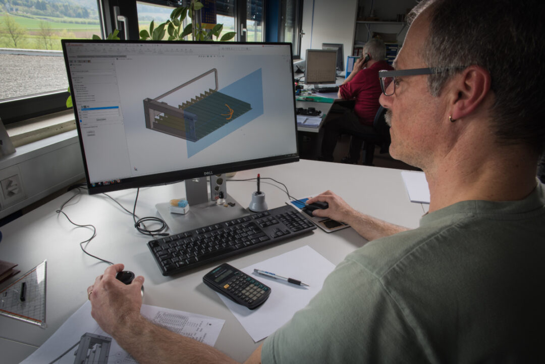 Un employé qui travail sur un logiciel graphique ou l'on peut apercevoir une maquette d'un composant ou machine.