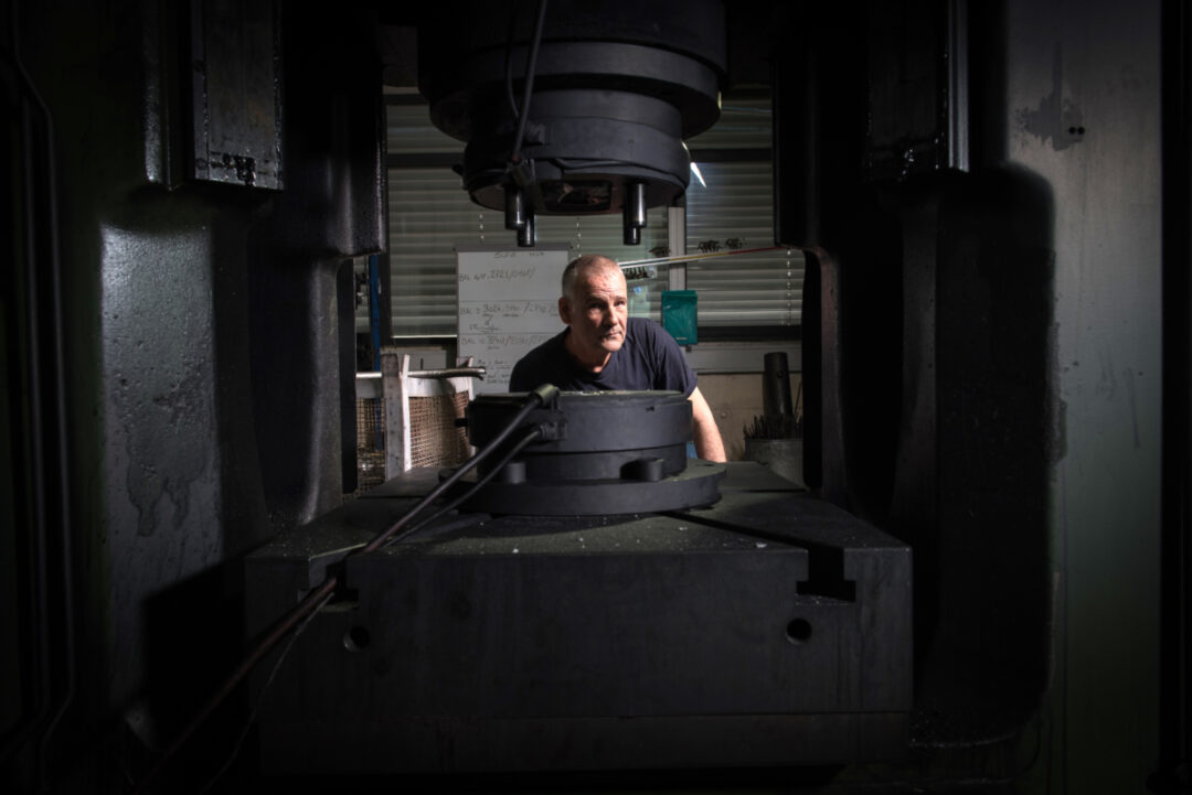 Machine en premier plan avec en arrière plan un employé qu'on peut apercevoir derrière la machine.