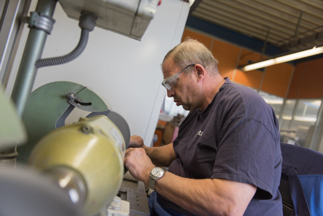 Employé qui porte des lunettes de protection et qui travail sur une machine.