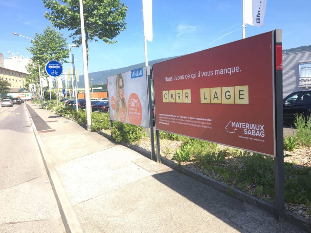 Pancarte "Nous avons ce qu'il vous manque" avec le mot "carrelage" dans la rue.