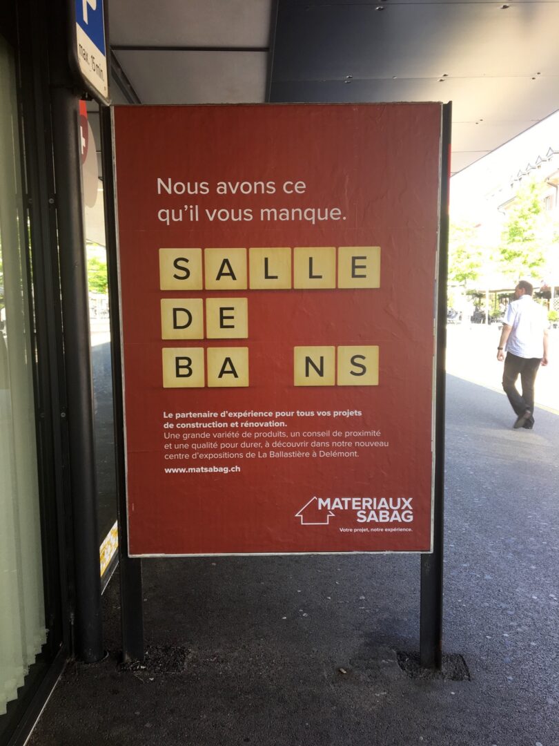 Pancarte "Nous avons ce qu'il vous manque" avec écrit "salle de bains" dans la rue.