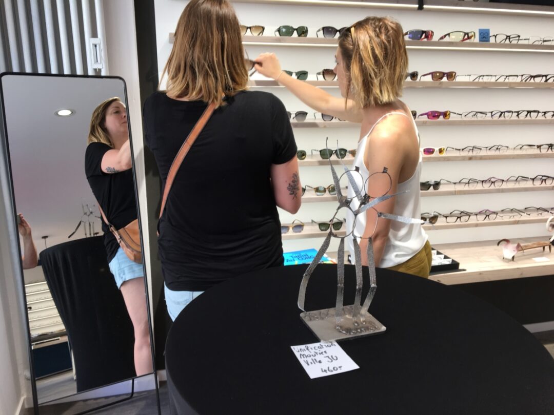 Deux personnes en train d'essayer des lunettes chez Houlmann optique.